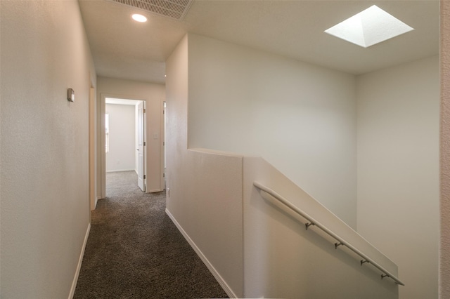 hall with a skylight and dark carpet