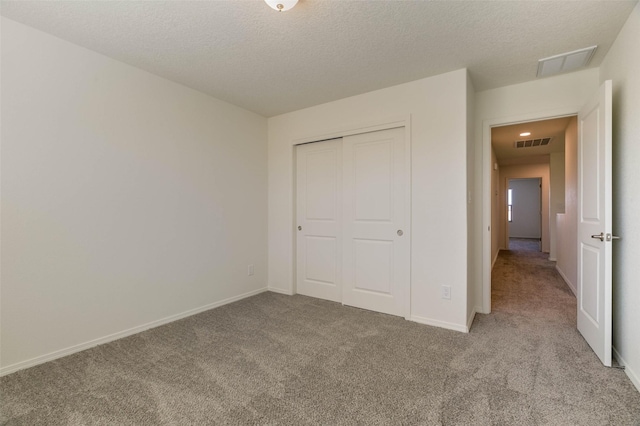 unfurnished bedroom with light colored carpet, a closet, and a textured ceiling