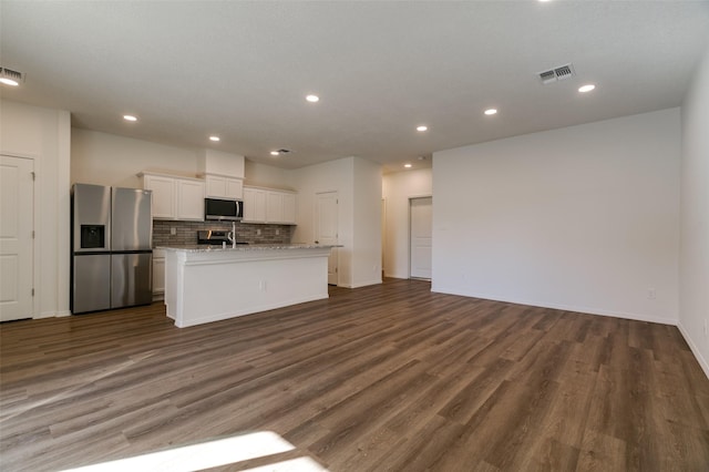 kitchen with dark hardwood / wood-style floors, white cabinetry, stainless steel appliances, and a center island with sink