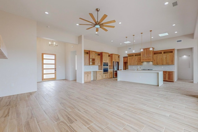 unfurnished living room with ceiling fan with notable chandelier, sink, and light hardwood / wood-style floors