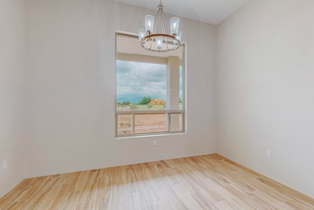 unfurnished room featuring a chandelier and light hardwood / wood-style flooring