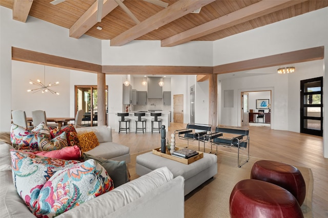 living room featuring ceiling fan with notable chandelier, light hardwood / wood-style floors, wood ceiling, and a high ceiling