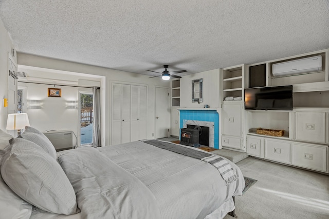 bedroom featuring a wood stove, a tile fireplace, an AC wall unit, light carpet, and ceiling fan