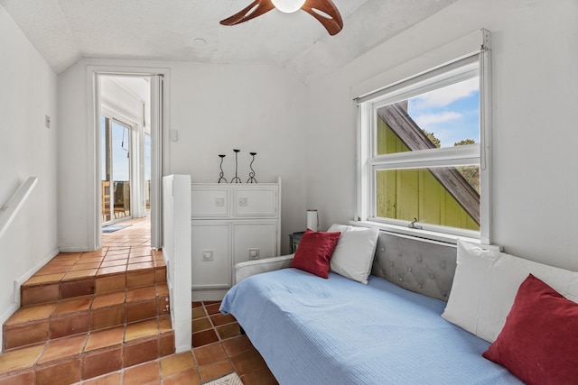 tiled bedroom featuring multiple windows, a textured ceiling, ceiling fan, and vaulted ceiling