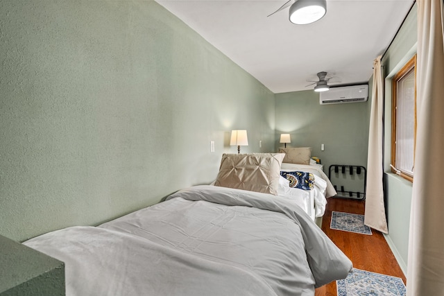 bedroom with an AC wall unit, ceiling fan, and hardwood / wood-style floors