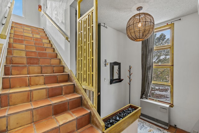 stairs with a wealth of natural light and a textured ceiling