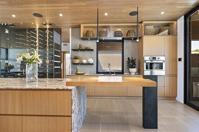 kitchen with light tile patterned floors, wood ceiling, sink, light stone counters, and oven