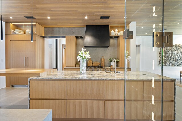 kitchen with wall chimney range hood, sink, refrigerator, light stone counters, and wooden ceiling