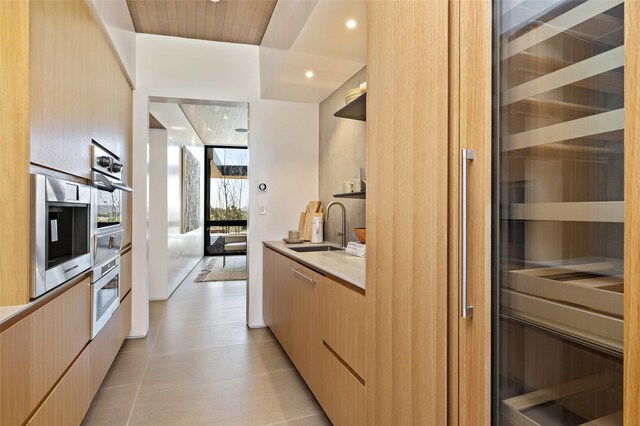 kitchen with light brown cabinetry, sink, beverage cooler, oven, and wall oven