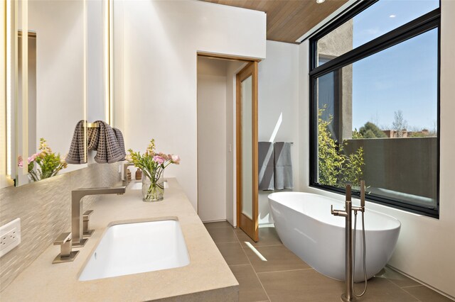 bathroom with a washtub, vanity, and tile patterned flooring