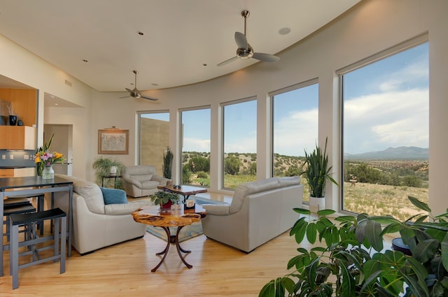 living room featuring ceiling fan, a mountain view, and light hardwood / wood-style floors