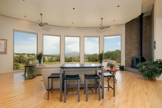 living room with ceiling fan, light wood-type flooring, and a wood stove