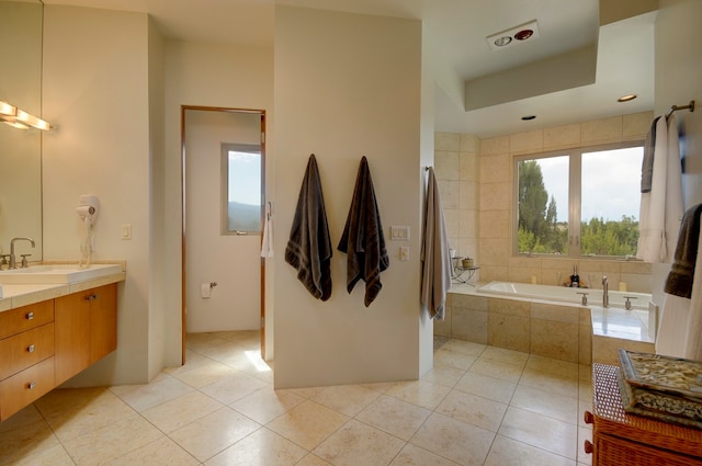 bathroom featuring tile patterned floors, vanity, and a relaxing tiled tub