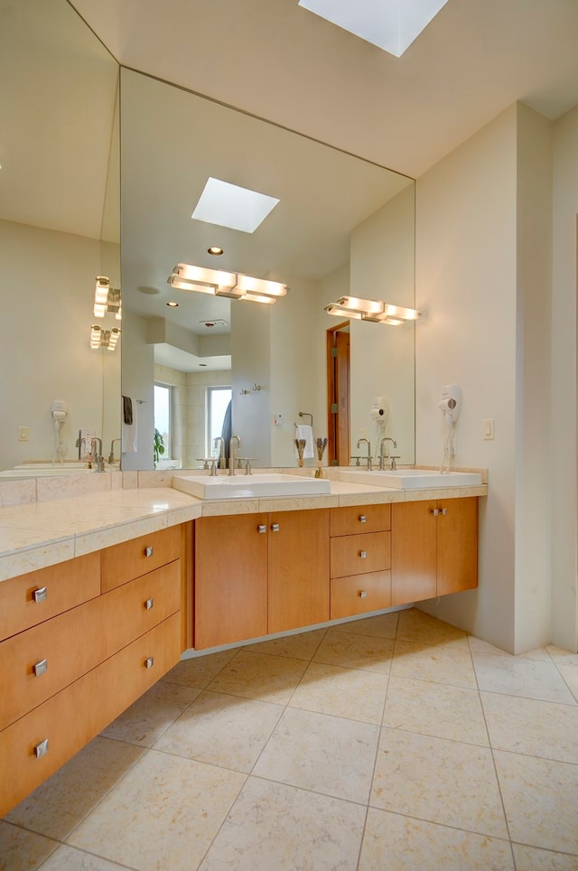 bathroom featuring a skylight, dual vanity, and tile patterned flooring