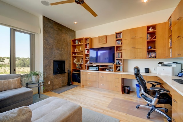 home office featuring ceiling fan, light wood-type flooring, tile walls, and built in desk