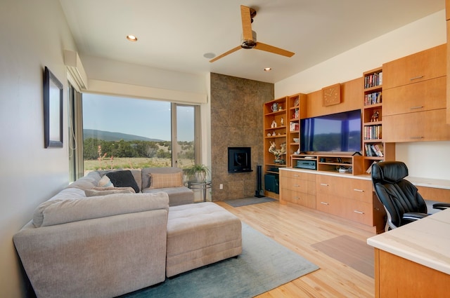 living room featuring ceiling fan, a fireplace, and light hardwood / wood-style floors