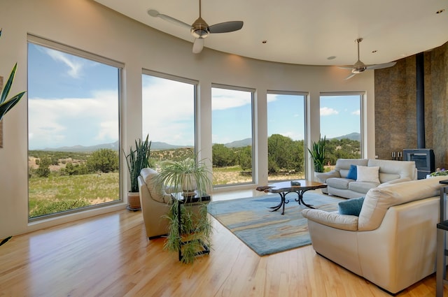 living room featuring a wood stove, light hardwood / wood-style flooring, and ceiling fan