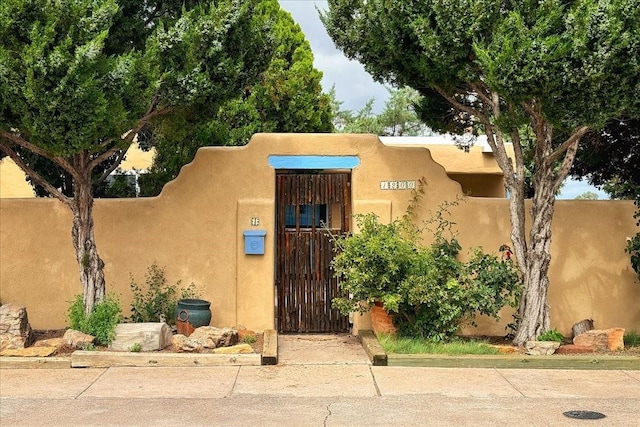 exterior space featuring stucco siding and a gate