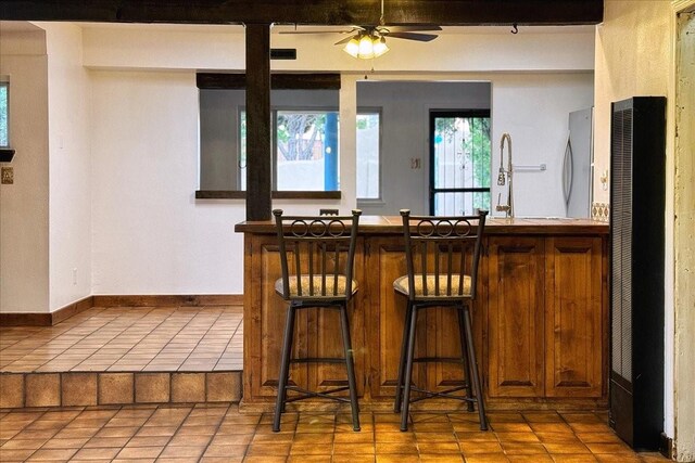 bar featuring stainless steel fridge, ceiling fan, and tile patterned flooring