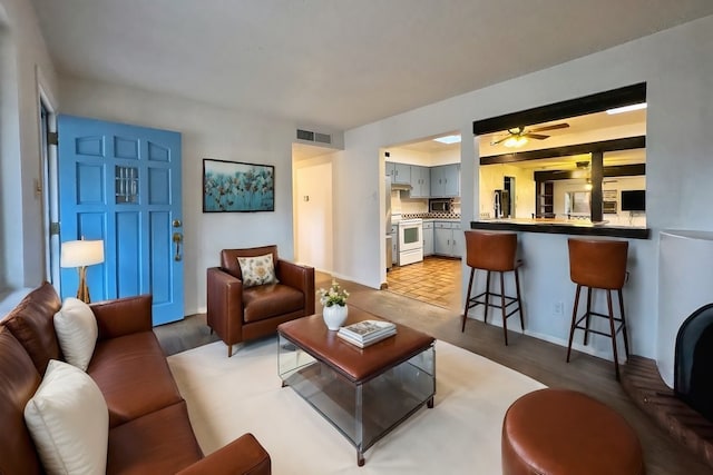 living room with light wood-style flooring, a ceiling fan, and visible vents