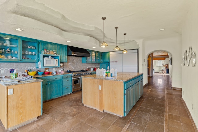 115 Waldo Mesa, Madrid, NM 87010 - kitchen with white appliances, an island with sink, tile patterned flooring, backsplash, and wall chimney exhaust hood