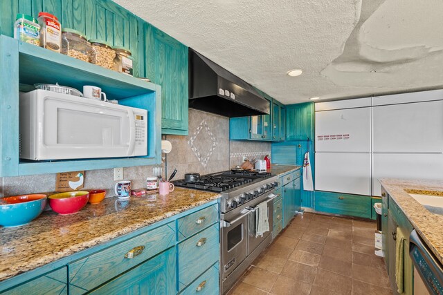 115 Waldo Mesa, Madrid, NM 87010 - kitchen with a textured ceiling, appliances with stainless steel finishes, light stone countertops, tasteful backsplash, and wall chimney exhaust hood