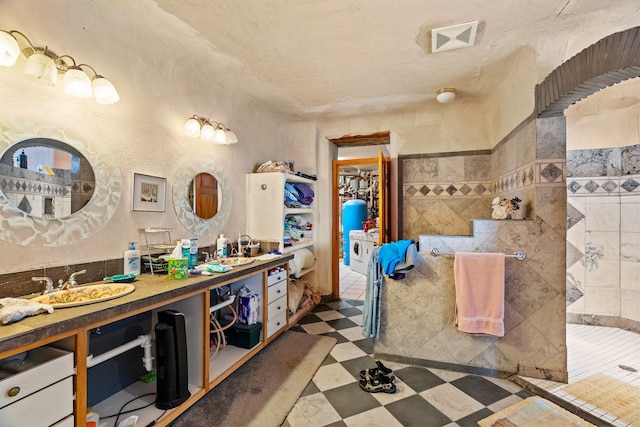 115 Waldo Mesa, Madrid, NM 87010 - bathroom featuring a shower, tile patterned flooring, tile walls, washer and dryer, and vanity