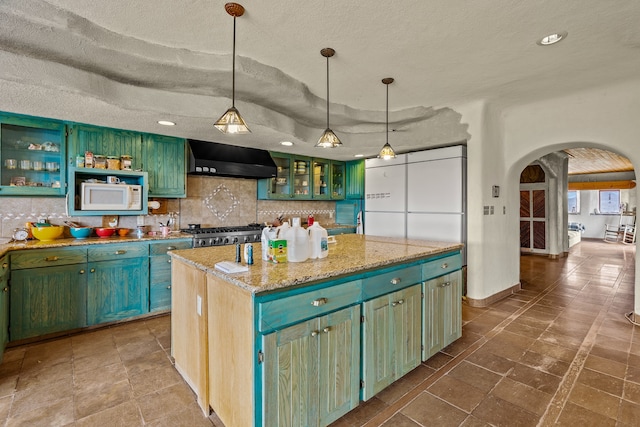 115 Waldo Mesa, Madrid, NM 87010 - kitchen featuring white microwave, a textured ceiling, a center island, and wall chimney exhaust hood