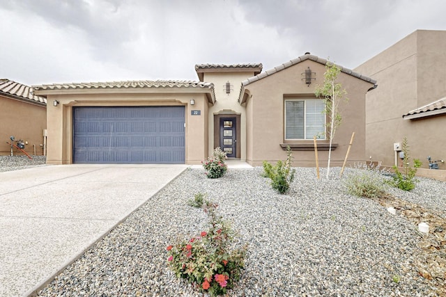 mediterranean / spanish-style home with an attached garage, a tiled roof, concrete driveway, and stucco siding