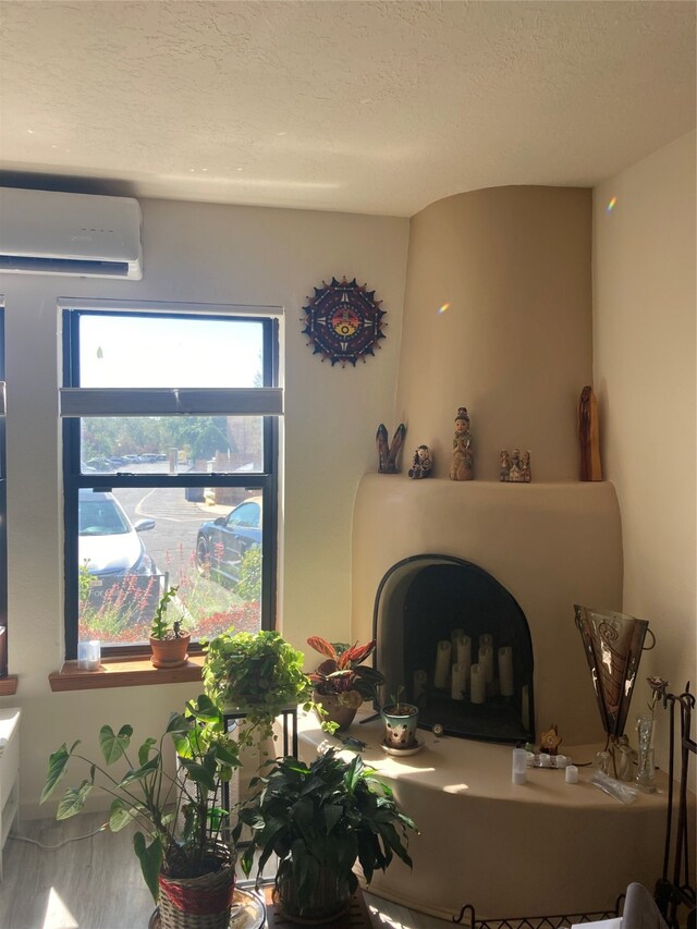 living room with a wall mounted air conditioner and a textured ceiling