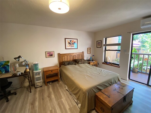 bedroom featuring light wood-type flooring, a wall unit AC, and access to outside