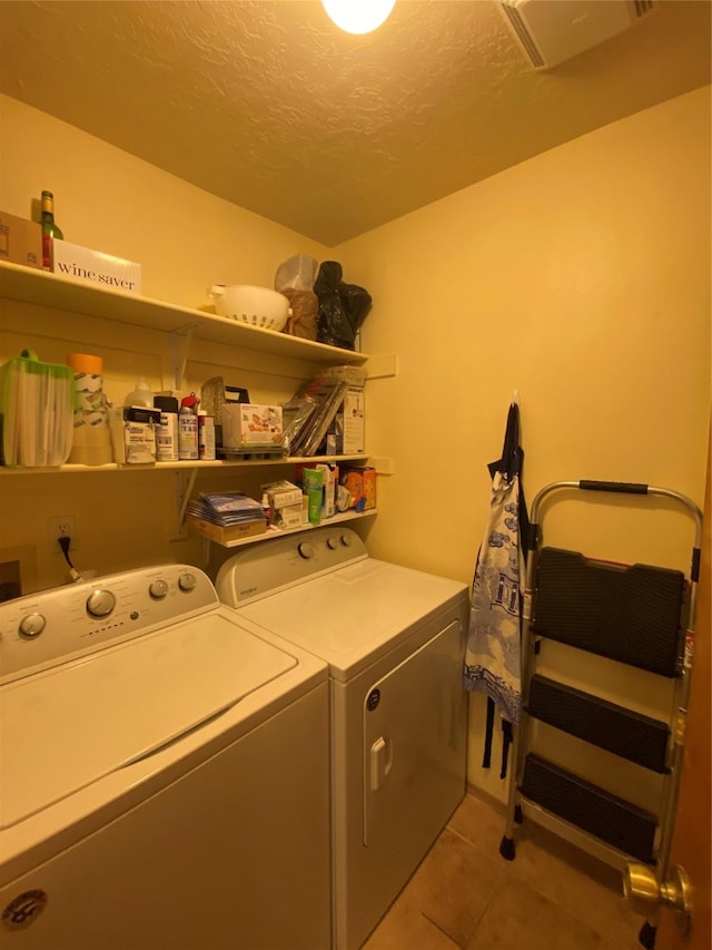 washroom featuring separate washer and dryer, a textured ceiling, and light tile patterned flooring