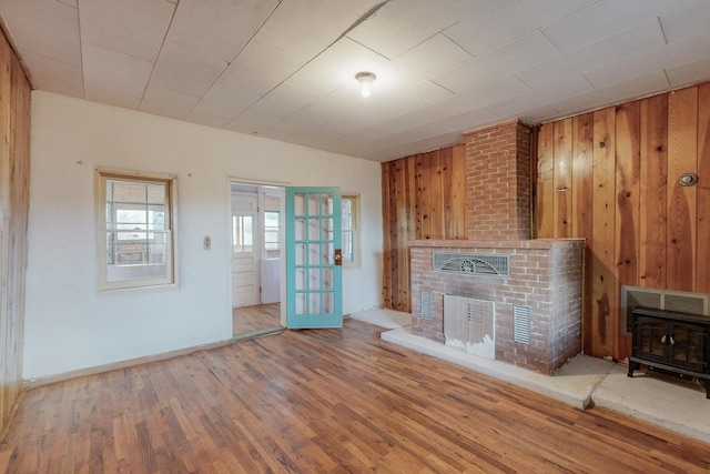 unfurnished living room featuring hardwood / wood-style flooring, wood walls, and a fireplace