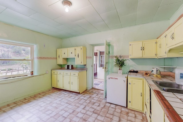 kitchen featuring tile counters, refrigerator, sink, and dishwasher