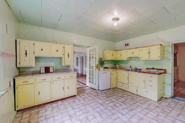 kitchen featuring white refrigerator and cream cabinetry