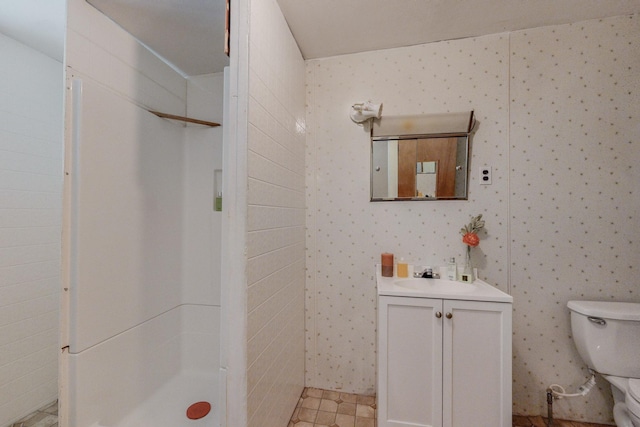 bathroom featuring toilet, vanity, and a shower