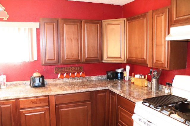 kitchen with light stone countertops and white range with gas cooktop