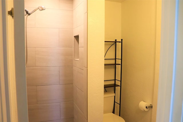 bathroom featuring toilet and a tile shower