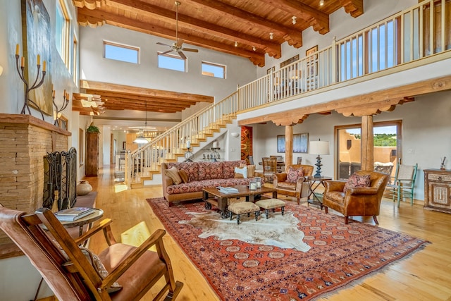 living room with ceiling fan, beam ceiling, a towering ceiling, ornate columns, and light hardwood / wood-style floors