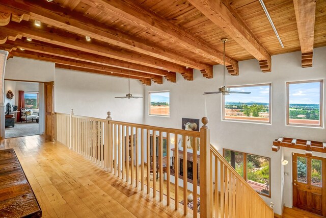 hallway featuring beamed ceiling, a wealth of natural light, wooden ceiling, and light hardwood / wood-style floors