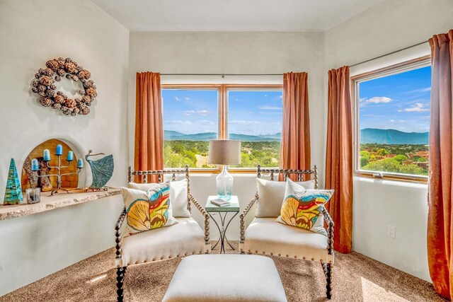 living area featuring a mountain view, a healthy amount of sunlight, and carpet