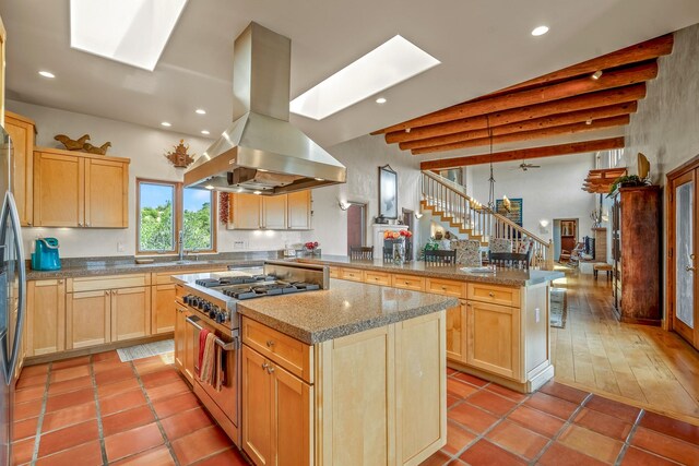 kitchen featuring appliances with stainless steel finishes, light tile patterned floors, island range hood, and a kitchen island