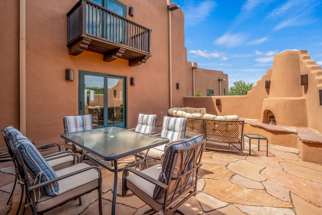 view of patio with a balcony and an outdoor living space with a fireplace