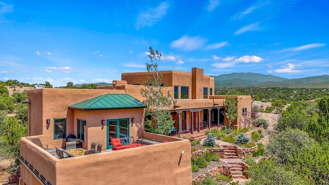 back of property with a patio, a mountain view, and an outdoor hangout area