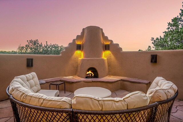 patio terrace at dusk featuring an outdoor living space with a fireplace