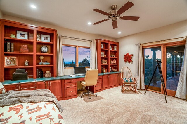 carpeted home office featuring ceiling fan