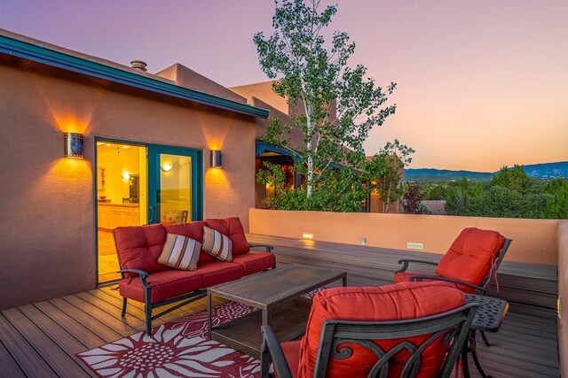 deck at dusk featuring an outdoor hangout area