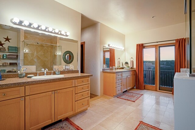 bathroom featuring a tile shower, double sink vanity, and tile patterned flooring