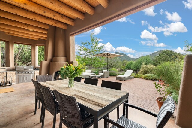 view of patio / terrace with an outdoor living space with a fireplace, a grill, area for grilling, and a mountain view