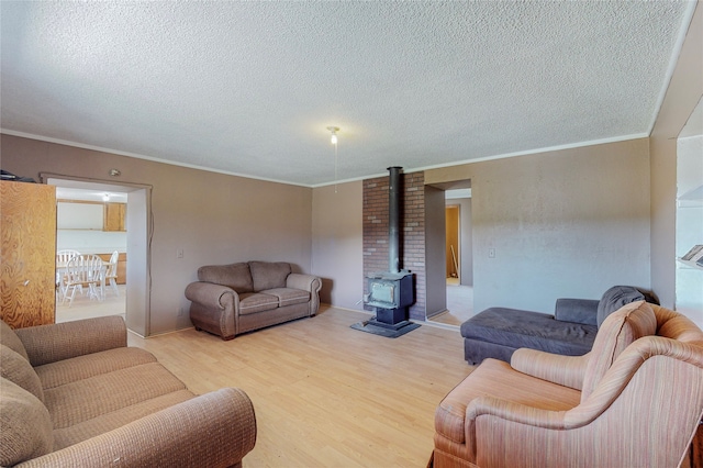 living room with a textured ceiling, crown molding, a wood stove, light hardwood / wood-style flooring, and brick wall